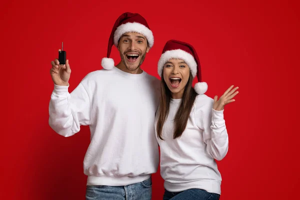 Noel Baba Şapkalı neşeli çift arabanın anahtarını tutuyor ve heyecanla bağırıyor. — Stok fotoğraf