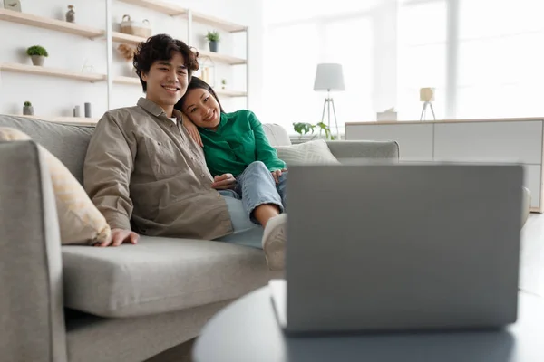Millennial couple asiatique regarder des films sur ordinateur portable en ligne, câlins sur le canapé à la maison, espace de copie — Photo