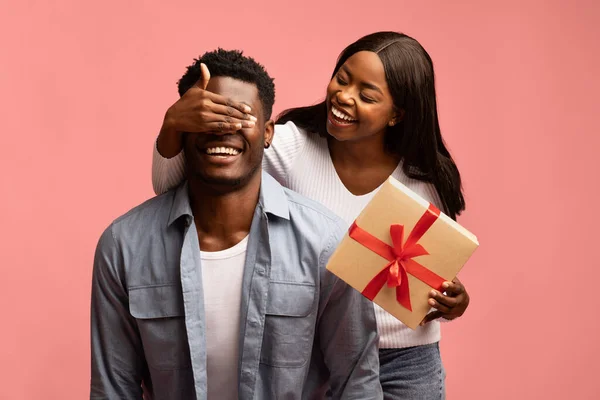 Pembe arka planda hediye kutusu olan Afrikalı Amerikalı genç bir çift. — Stok fotoğraf