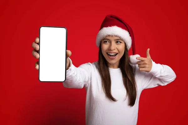 Phone Mockup. Excited Woman In Santa Hat Pointing At Blank Smartphone — Stock Photo, Image