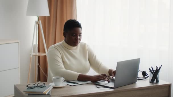 Mujer de negocios negra con sobrepeso usando computadora portátil sentada en la oficina — Vídeo de stock