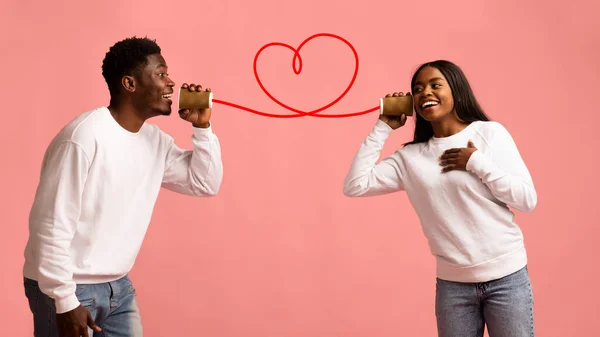 Jong zwart paar met kan telefoon op roze achtergrond — Stockfoto