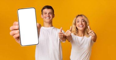 Boş akıllı telefon ekranı ve başparmakları gösteren heyecanlı çift