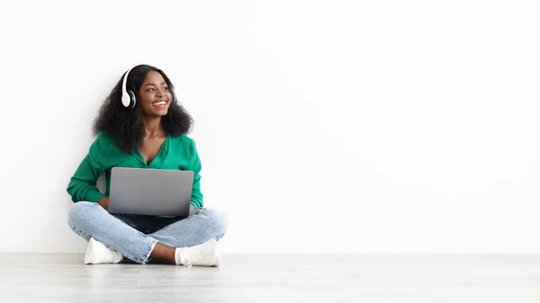 Positivo joven negro mujer usando ordenador portátil y auriculares — Foto de Stock