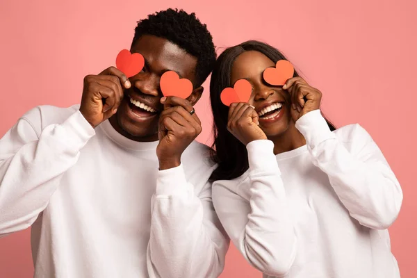 Fechar-se de par que mantém corações de amor vermelhos sobre olhos — Fotografia de Stock