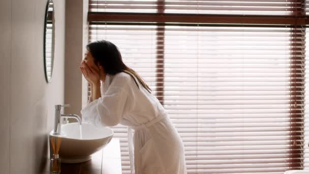 Молода красива азіатська леді одягнена шовк roobe прання обличчя у ванній — стокове відео