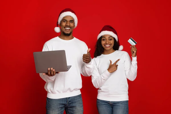Bilgisayarı ve kredi kartı olan Noel Baba şapkalı mutlu çift. — Stok fotoğraf