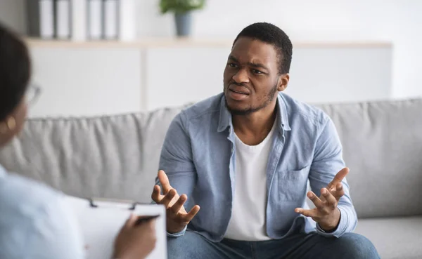Psychologist helping depressed young black man, giving consultation to male patient at office — Stock Photo, Image