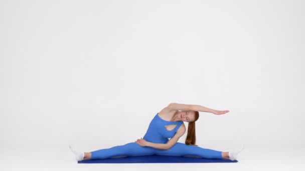 Vücut esnemesi. Jimnastikçi Kadın Ayrı Konumda Oturuyor ve Yan Dönüşler Yapıyor — Stok video
