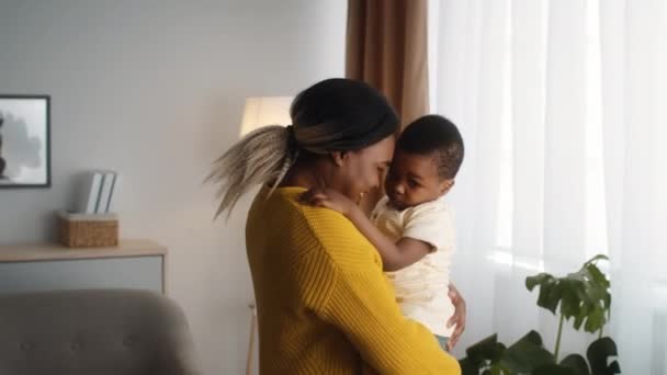 Milující černošky maminka drží malého syna na rukou, lepení doma — Stock video