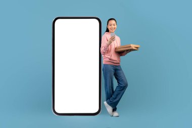 Cute asian millennial woman order pizza online, using mobile app