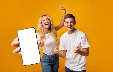 Excited Young Couple Showing Big Smartphone With White Screen And Celebrating Success