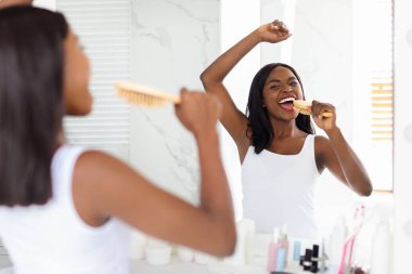 Joyful Black Lady Singing With Hairbrush While Looking In Mirror In Bathroom