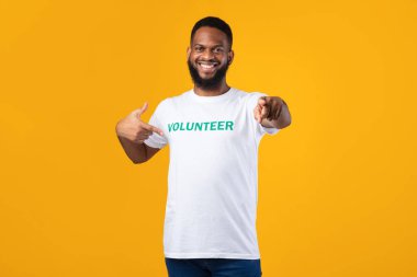 Black male volunteer pointing at t-shirt and at camera, studio