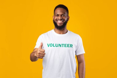 Happy African American Male Volunteer Gesturing Thumbs-Up Over Yellow Background