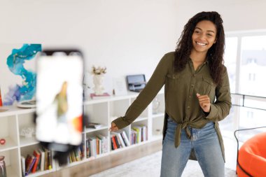 Neşeli siyah kadın cep telefonuyla dans videosu çekiyor.