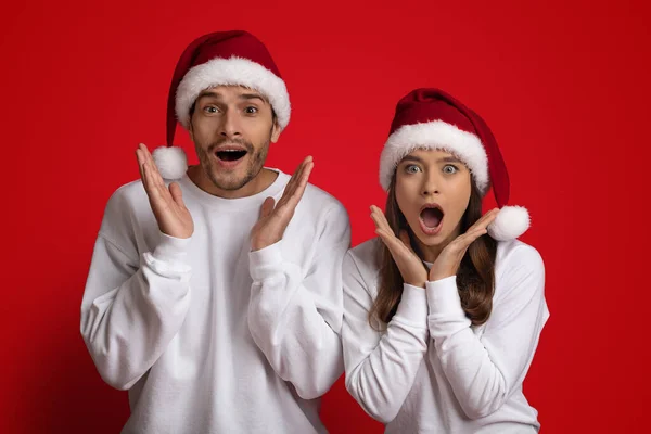 Xmas Sales. Surprised Man And Woman In Santa Hats Exclaiming With Excitement — Stock fotografie