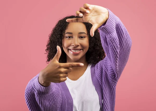 Cheerful black woman making picture frame with fingers, looking at camera and smiling for photo on pink background — Stockfoto