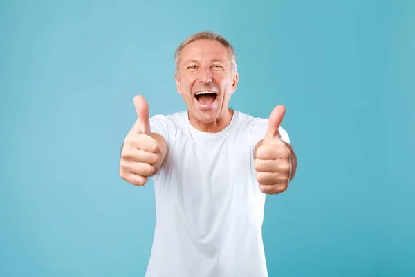 Excited mature man gesturing thumbs up and smiling — Stockfoto