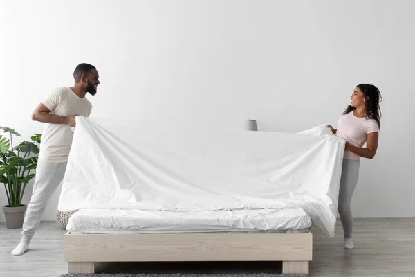 Feliz sonriente joven afroamericano novio y novia hacer cama, mantener cuadros, divertirse juntos —  Fotos de Stock