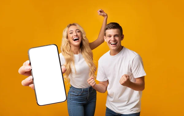 Excited Young Couple Showing Big Smartphone With White Screen And Celebrating Success — Stok fotoğraf
