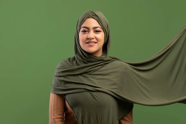 Portrait of beautiful muslim woman in hijab posing over khaki background, looking and smile at camera — Stok Foto