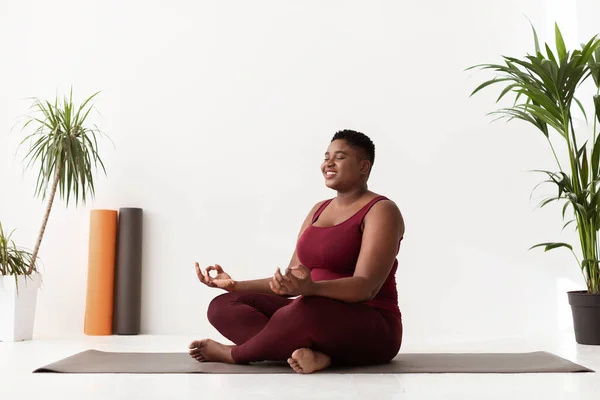 Positive fat black lady in sportswear having yoga practice —  Fotos de Stock