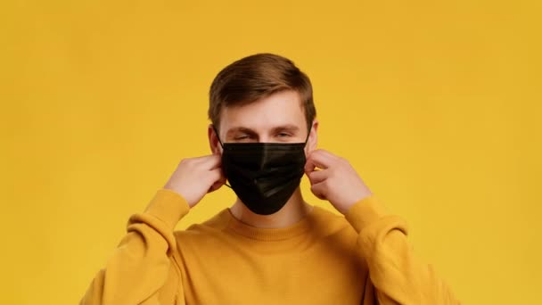 Man Taking Off Face Mask Smiling To Camera, Yellow Background — Stock video