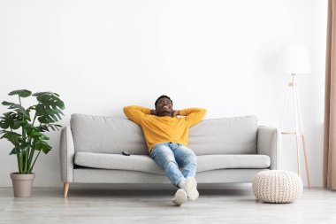 Relaxed black guy in casual resting on sofa at home