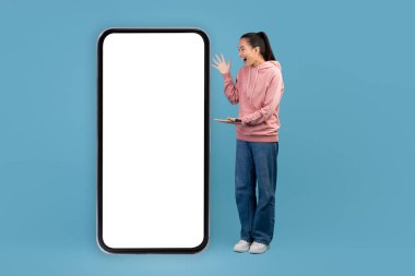 Emotional chinese woman looking at smartphone empty screen