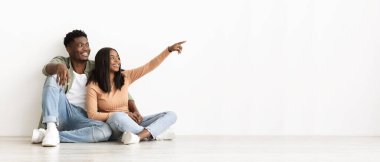 Cheerful african american couple pointing at copy space