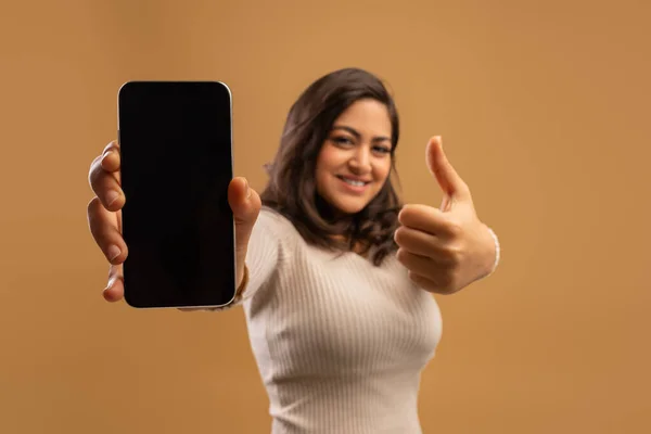 Mujer árabe emocionada mostrando un enorme teléfono inteligente con pantalla en blanco y pulgar hacia arriba, demostrando aplicación móvil o sitio web —  Fotos de Stock