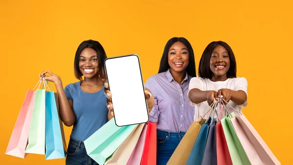 Online Sales. Thre Black Females With Bright Shopping Bags Showing Blank Smartphone — Stockfoto