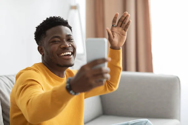 Cheery black man having online party with friends, using smartphone — Stok fotoğraf