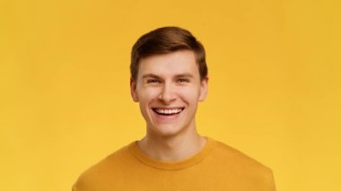 Man Smiling Raising Eyebrows Looking At Camera Over Yellow Background