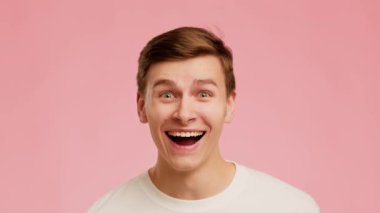Amazed Young Man Smiling Looking At Camera Over Pink Background