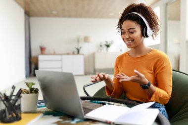 Siyah bir kadın bilgisayarı kullanıp web kamerasında konuşuyor.