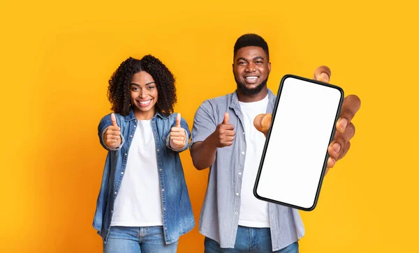 Zwart paar toont lege smartphone scherm en duimen omhoog — Stockfoto