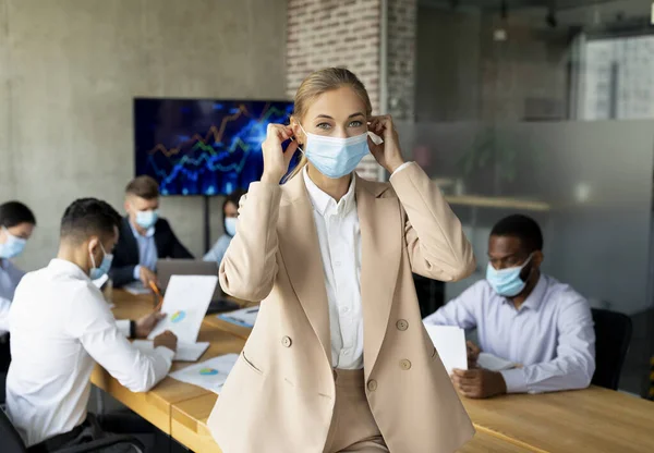 Businesswoman Putting On Medical Face Mask Before Meeting With Colleagues In Office — Stock Photo, Image