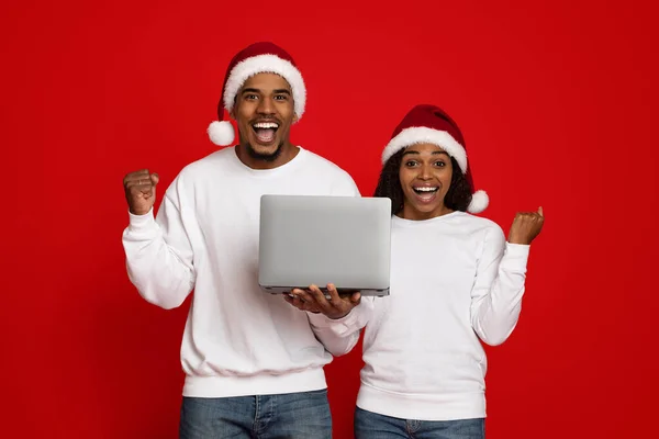 Happy black couple champions holding laptop and raising hands up — ストック写真