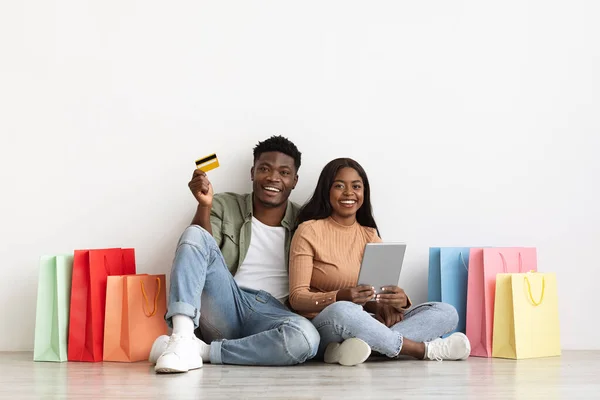 Emotional african american couple shopaholics using pad and credit card — Foto de Stock