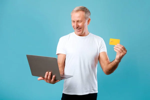 Vzrušený dospělý muž držící kreditní kartu a notebook — Stock fotografie