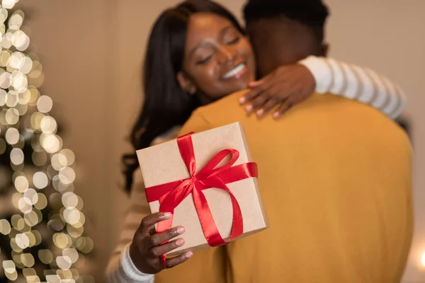 Black Couple Hugging Holding Gift Standing Near Xmas Tree Indoor — Fotografia de Stock