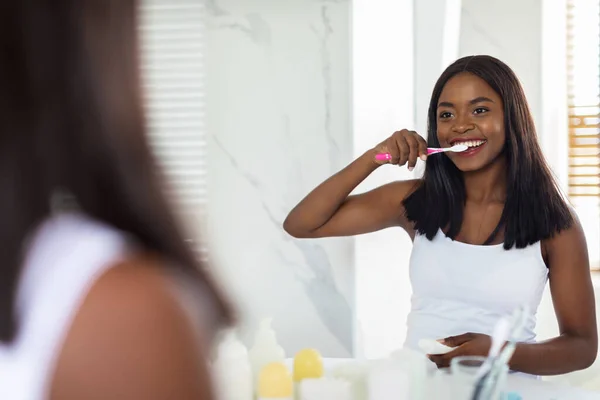 Wanita muda Afrika Amerika cantik Menyikat Giginya Dengan sikat gigi di kamar mandi — Stok Foto