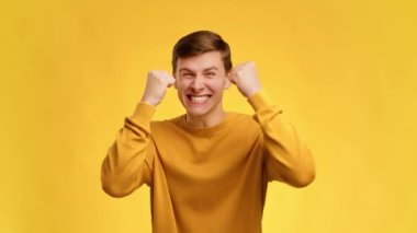 Millennial Man Shaking Fists Celebrating Success Posing Over Yellow Background
