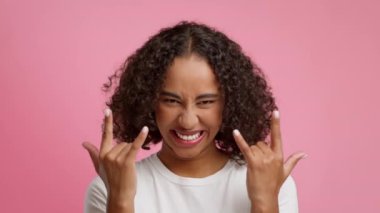 Joyful African American Woman Showing Rock Gesture Over Pink Background