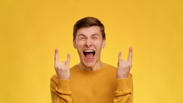 Emotional Guy Showing Rock Gesture Shouting On Yellow Background — Wideo stockowe