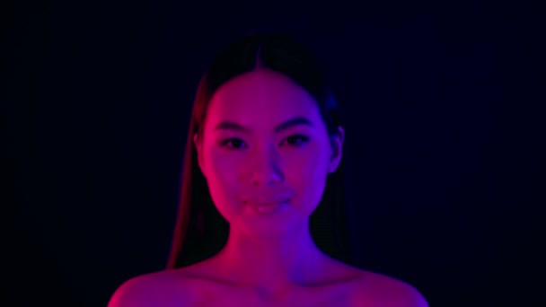 Sensual Beauty. Young Asian Woman With Naked Shoulders Standing Under Neon Lights — стокове відео