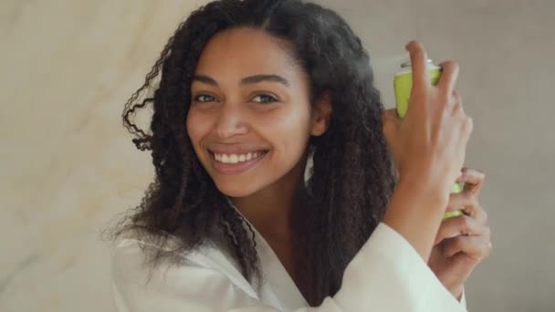 Hair Care cosmetics. Young african american woman spraying special conditioner on curly care, making hairstyle at home — Video Stock