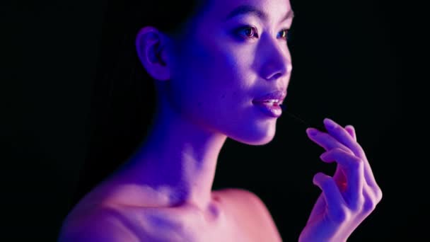 Wanita Asia sensual Menerapkan Lipstik Dengan Brush, Berdiri Di Bawah Terang Neon Terang Terang — Stok Video